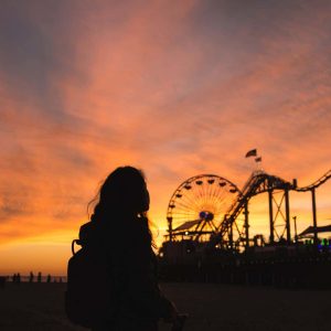 Woman looking at sillhousette of a roller coaster at sunset